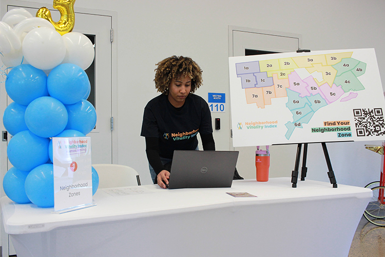 D3 employee Jordan Graves standing at a booth while using a computer at the NVI Homecoming event