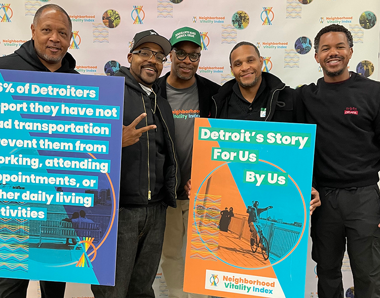 A group of men holding signs with NVI data and smiling at the NVI Homecoming event