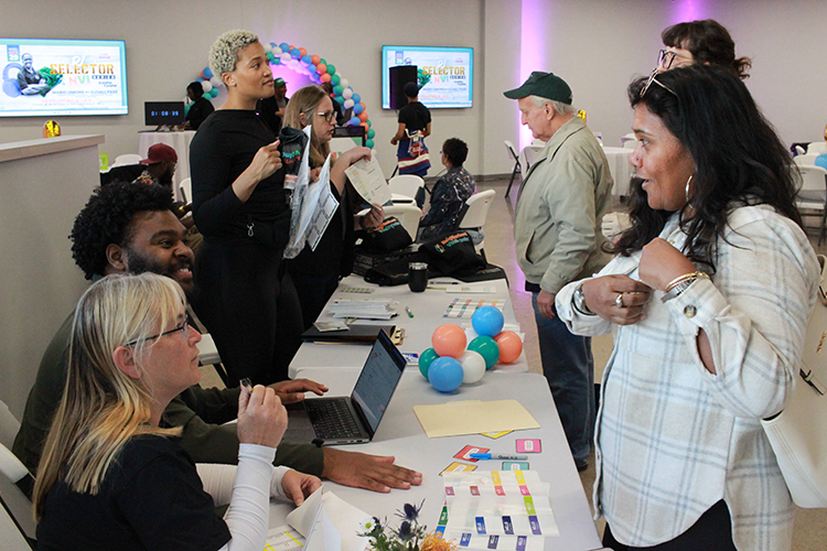 A table with D3 employees welcoming guests to the NVI Homecoming event